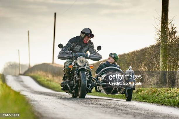 senior man and grandson riding motorcycle and sidecar along rural road - motorbike sidecar stock pictures, royalty-free photos & images