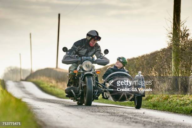 senior man and grandson riding motorcycle and sidecar along rural road - old motorcycles imagens e fotografias de stock