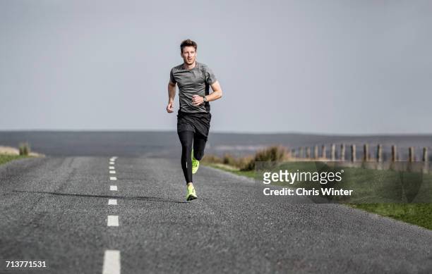 male runner running along rural moorland road - gray shorts stockfoto's en -beelden