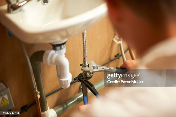 male trainee plumber using adjustable spanner on pipework in college workshop - adjustable wrench stock pictures, royalty-free photos & images