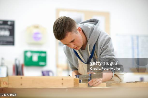 male teenage carpentry student adjusting wood clamp in college workshop - one teenage boy only fotografías e imágenes de stock