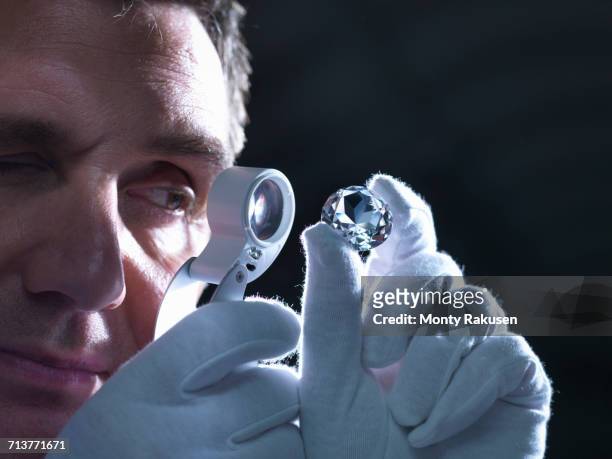 jeweller inspecting replica diamonds with loupe - jeweller stock pictures, royalty-free photos & images