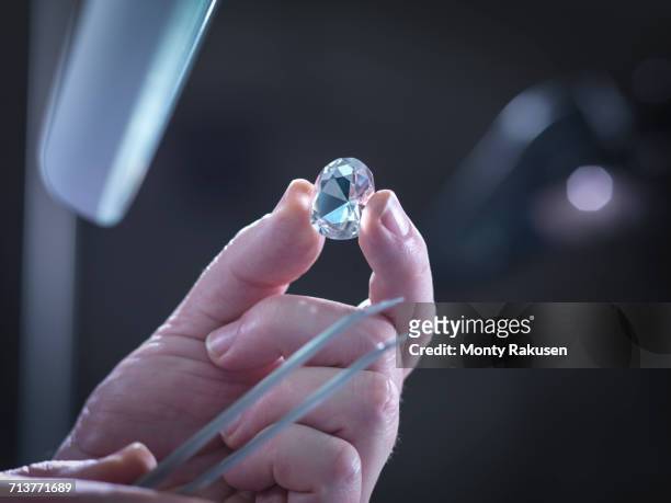 jeweller inspecting replica diamonds in hand - examining diamond stock pictures, royalty-free photos & images