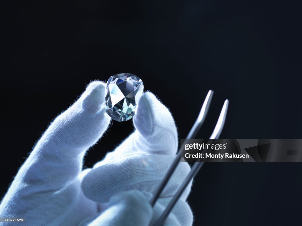Jeweller inspecting replica diamonds with gloved hand