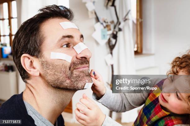 girl sticking adhesive plaster onto fathers chin - head bandage stock pictures, royalty-free photos & images