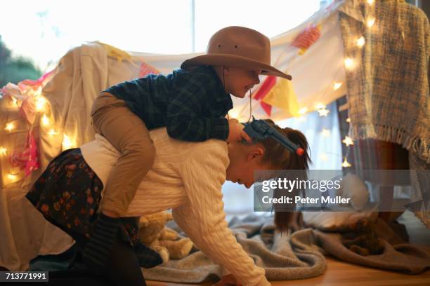 boy in cowboy hat getting piggyback ride from sister - toy gun stock pictures, royalty-free photos & images