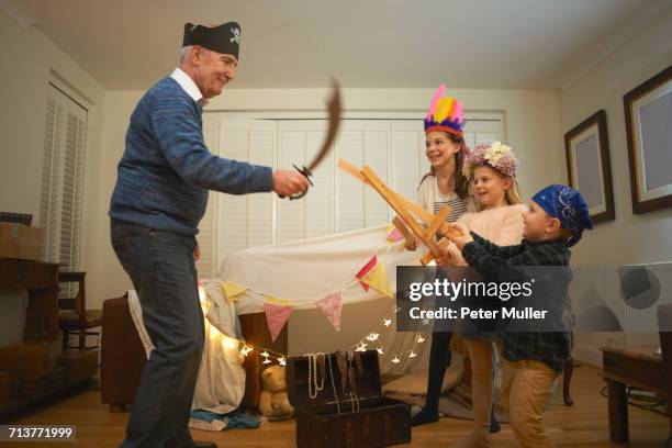 senior man in pirate hat having sword fight with dressed up grandchildren - girls wrestling stock pictures, royalty-free photos & images