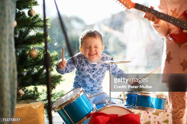 boy and sister playing toy drum kit and guitar on christmas day - playing drums fotografías e imágenes de stock