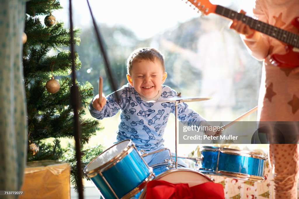 Boy and sister playing toy drum kit and guitar on christmas day