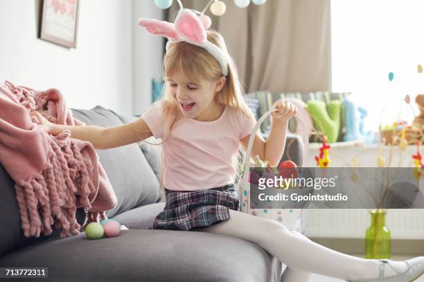 girl finding easter eggs under sofa blanket - finden stock-fotos und bilder