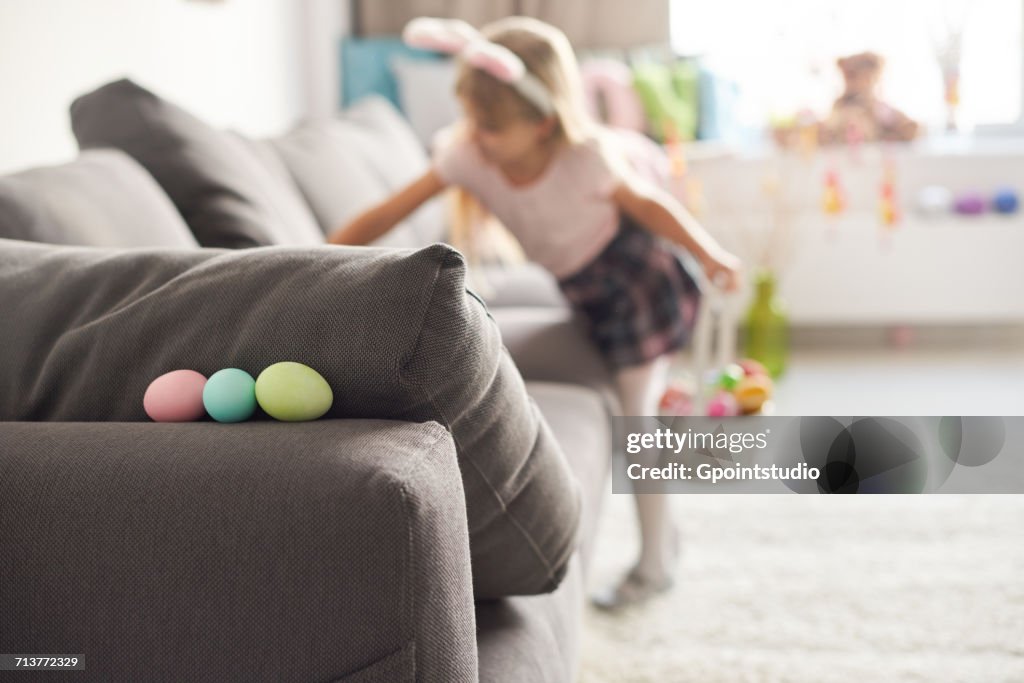 Girl searching for easter eggs on sofa