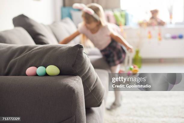 girl searching for easter eggs on sofa - easter egg hunt stock pictures, royalty-free photos & images