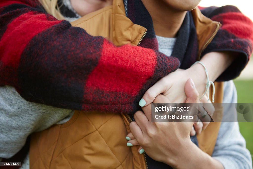Cropped close up of woman hugging and holding boyfriends hands