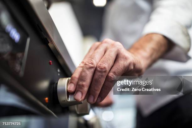 chef turning on oven, close-up - piano del fornello foto e immagini stock