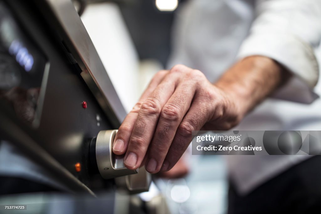 Chef turning on oven, close-up
