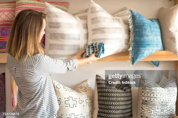 rear view of female interior designer trying textile against cushions in retail studio - multi platinum selling stock pictures, royalty-free photos & images