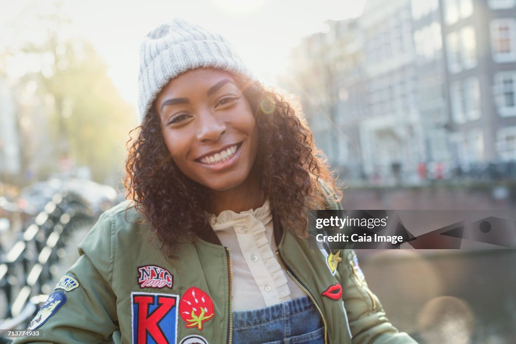 Portrait smiling young woman on sunny urban autumn street