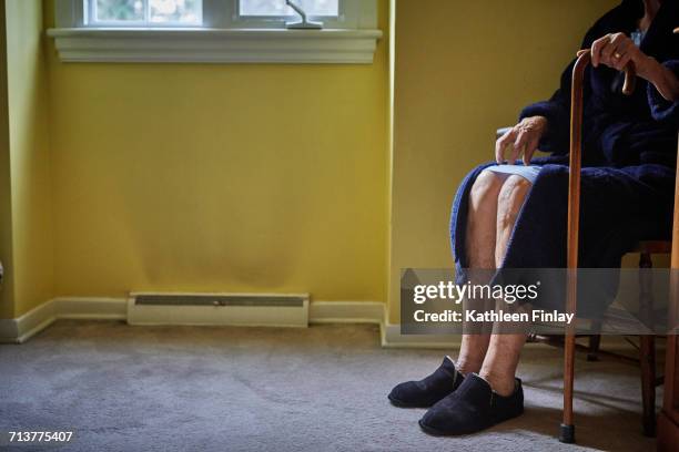 senior woman sitting in chair, holding walking can, low section - vulnerability stock-fotos und bilder