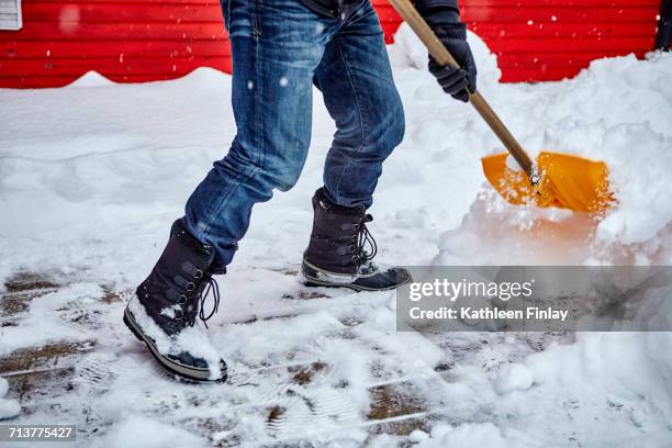 man shovelling snow from pathway, low section - shovel fotografías e imágenes de stock