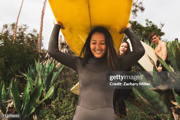 three friends walking towards beach, carrying surfboards - carrying stock pictures, royalty-free photos & images