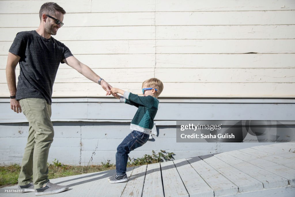 Boy pulling father up wooden ramp