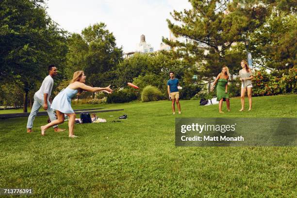 five adult friends playing with flying disc in park - frisbee stock pictures, royalty-free photos & images