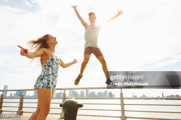 young man jumping mid air on sunlit waterfront, new york, usa - panorama nyc day 2 foto e immagini stock