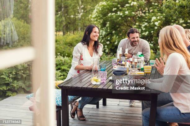 happy family and friend sitting at dining table in back yard - garden furniture foto e immagini stock