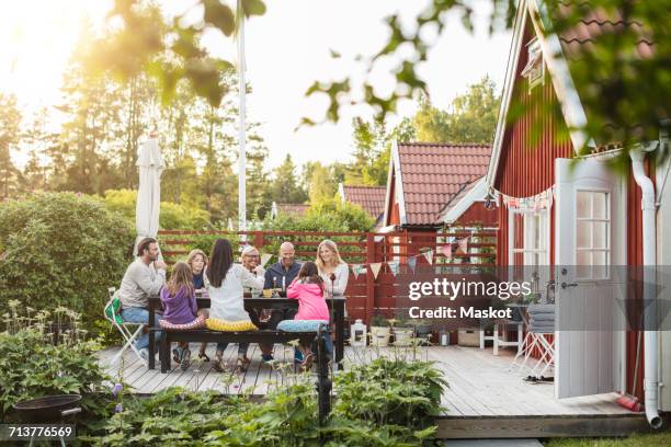 happy family and friends eating at garden lunch party in back yard - family back yard stockfoto's en -beelden