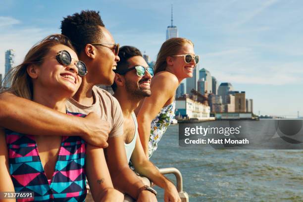 four adult friends looking out from river waterfront, new york, usa - new york city life stock pictures, royalty-free photos & images