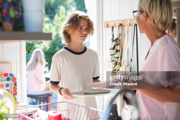 mother and son holding plates in kitchen at home - stoneware stock pictures, royalty-free photos & images