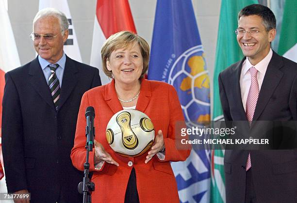 German Chancellor Angela Merkel poses with the ball of the 2006 Fifa World Cup final, handed over by German World Cup Organizing Committee head Franz...