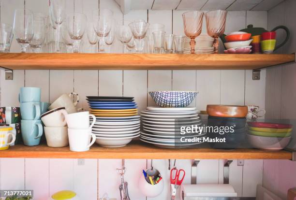 crockery and drinking glasses on shelves in kitchen at home - plate set stock pictures, royalty-free photos & images