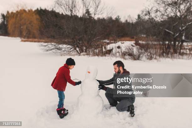 father and daughter making snowman - making a snowman stock pictures, royalty-free photos & images