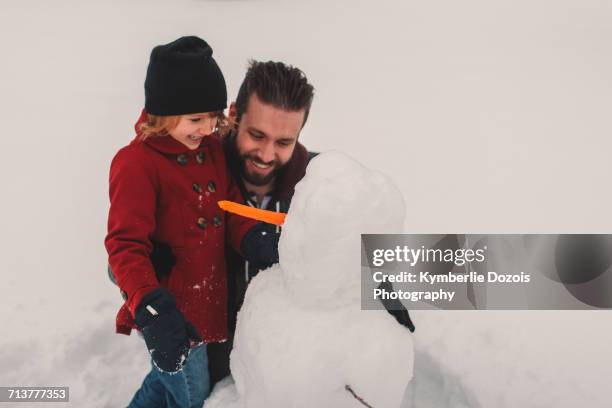 father and daughter making snowman - making a snowman stock pictures, royalty-free photos & images