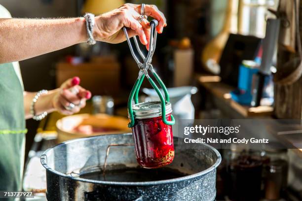 womans hands inserting beetroot preserves jar into saucepan - メイソンジャー ストックフォトと画像