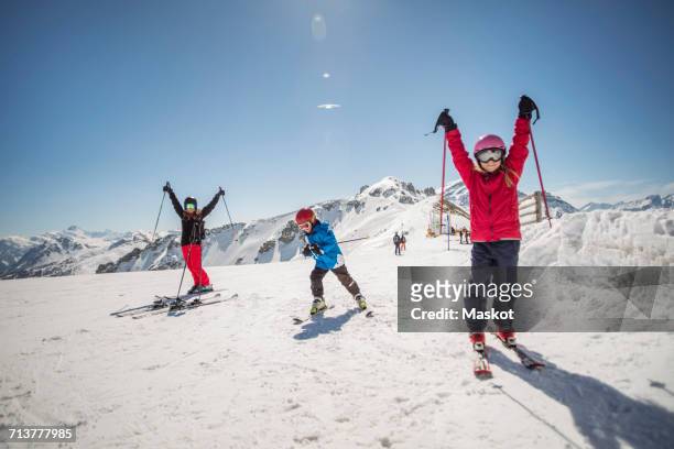 full length of family enjoying while skiing against clear sky - alpine stock pictures, royalty-free photos & images