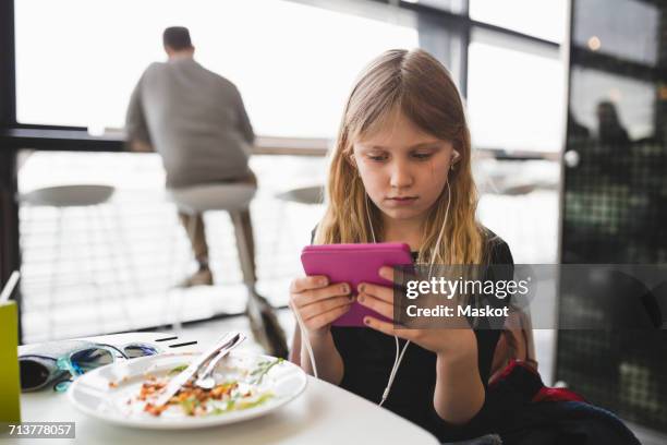 girl using digital tablet while sitting at table in restaurant - restaurant kids stock-fotos und bilder