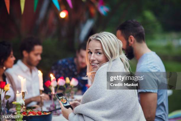 portrait of smiling woman photographing food while sitting with friends at garden party - memorial garden stock pictures, royalty-free photos & images