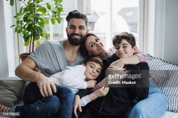 portrait of happy family enjoying on sofa in living room at home - nahöstlicher abstammung stock-fotos und bilder