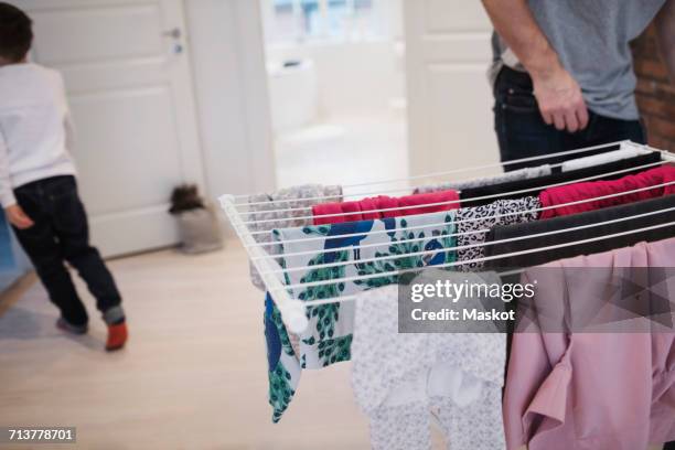 father and son by clothes rack at home - drying stock pictures, royalty-free photos & images
