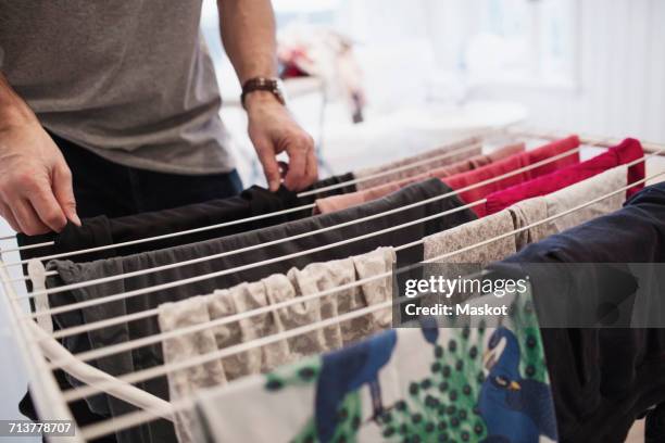 midsection of man drying clothes on rack at home - secado fotografías e imágenes de stock