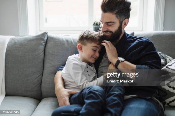 Father and son while sitting on sofa at home