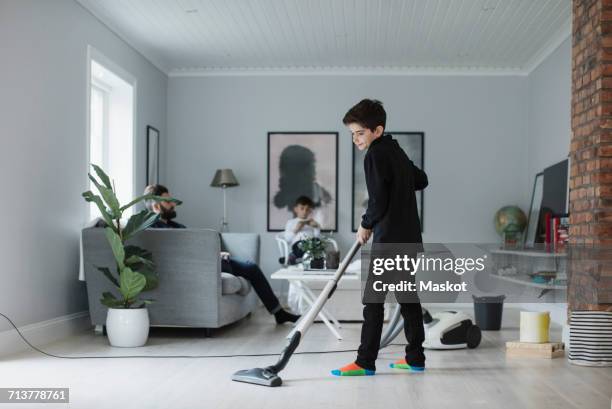 boy vacuuming floor in living room at home - arab home stock pictures, royalty-free photos & images