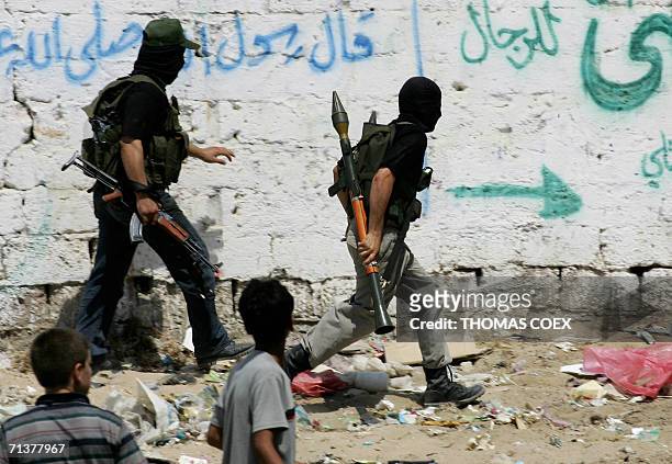 Palestinian masked activists run during fighting with israeli soldiers in a street of the Gaza Strip town of Beit Lahiya, 06 July 2006. Israeli tanks...