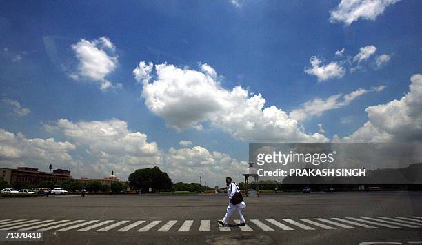 Man crosses the road as pre-monsoon clouds loom over Rajpath in New Delhi, 06 July 2006. The Indian Meteorological Department, who earlier forecasted...