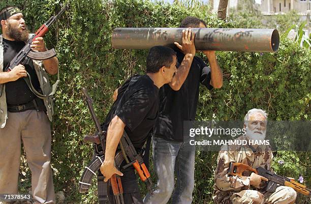 Palestinian militant rests on his shoulder a home made type of "rocket propelled grenade" he and others watch an on coming Israeli tank during armed...