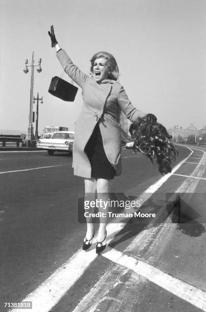American commedienne and entertainer Joan Rivers jumps into the air, her purse over an outstretched arm and a wig in her other hand, as she tries to...