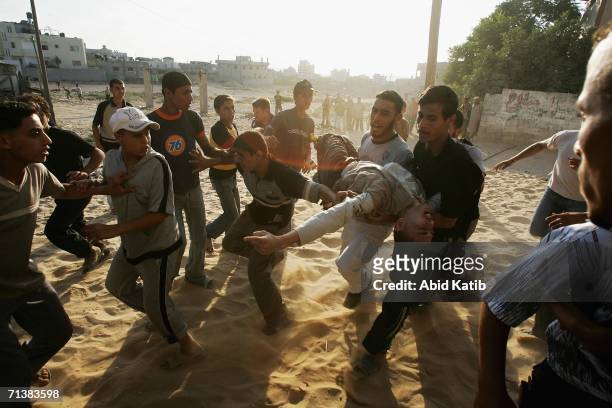 Palestinians carry a wounded man after Israeli troops opened fire on July 6, 2006 in Beit Lahia, northern Gaza Strip. Israeli infantry and armor...