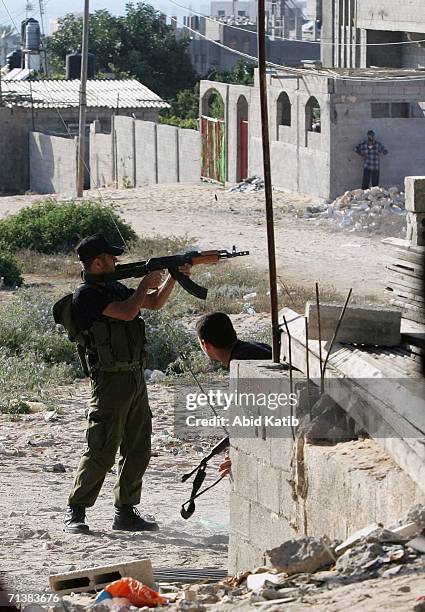 Palestinian fighter fires a gun during clashes with an Israli tank on July 6, 2006 in Beit Lahia, northern Gaza Strip. Israeli infantry and armor...